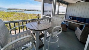 A balcony with a table and chairs, overlooking a body of water and a dock.