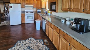 Une cuisine avec des meubles en bois, un réfrigérateur blanc, une cuisinière et une machine à café.