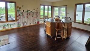 Une pièce spacieuse avec une table à manger en bois, des chaises et une vue sur un lac, visible à travers de grandes fenêtres.