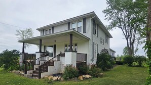 Une maison à deux étages avec un porche à l’avant, un escalier menant à l’entrée et une pelouse bien entretenue.
