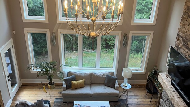Un salon spacieux avec un haut plafond, de grandes fenêtres, une cheminée et un lustre.