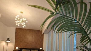Ein modernes Schlafzimmer mit einem großen Bett, einer Couch, einem flauschigen Teppich und einer hohen Pflanze.