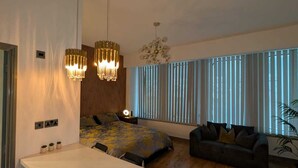 Ein modernes Wohnzimmer mit großem Fenster, einer Couch, einem Esstisch und zwei Pendelleuchten.