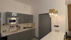 Eine moderne Küche mit integriertem Mikrowellenherd, Spüle und Essbereich mit weißem Tisch und Stühlen.
