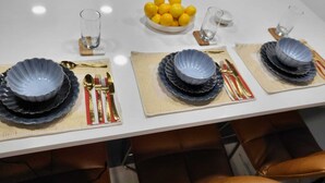 A dining table set with plates, cutlery, and glasses, with a bowl of lemons and a glass of water on the table. - Romantic Hide Out
 (Stamford)