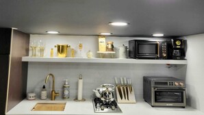 A modern kitchen with a gas stove, microwave, and oven. There are shelves with various kitchen items and a sink with a faucet. - Romantic Hide Out
 (Stamford)