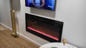 A modern living room with a television, fireplace, and round marble table with snacks. - Romantic Hide Out
 (Stamford)