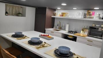 Une cuisine moderne dotée d’un îlot central, de meubles blancs et d’une variété d’ustensiles de cuisine et d’appareils électroménagers.