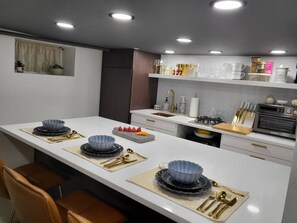 A modern kitchen with a central island, white cabinetry, and a variety of kitchenware and appliances. - Romantic hideout. 1Br. Lower Level (Stamford)