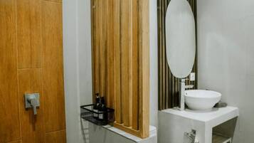 Une salle de bain avec une porte en bois, un lavabo blanc et un miroir.