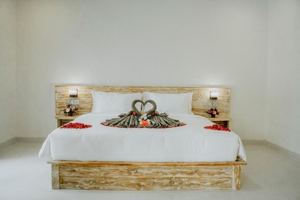 Una cama con cabecera de madera, ropa de cama blanca y almohadas decorativas con forma de cisne.