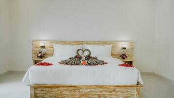 Una cama con cabecera de madera, ropa de cama blanca y almohadas decorativas con forma de cisne.