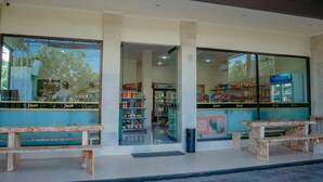 A JMart store with large glass windows, a central entrance, and two wooden benches outside. - Bingin Garden Uluwatu (Pecatu)