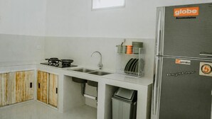 A compact kitchen with a gas stove, sink, and a refrigerator with a 'globe accommodation' sticker. - Bingin Garden Uluwatu (Pecatu)