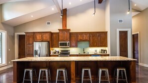 A spacious kitchen with wooden cabinets, a large island with stools, stainless steel appliances, and pendant lighting. - Welcome to Little Blanco! Bonus: Free Golf During Your Stay! (Concan)