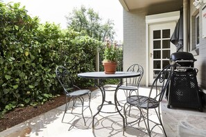 An outdoor patio with a round table and four chairs, a potted plant, and a grill. - Little Terrace Bowral 1 (Bowral)