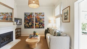 A cozy living room with a fireplace, a round wooden coffee table, a sofa, and two large butterfly-themed paintings.