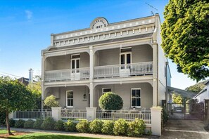 A two-story building with a balcony on the second floor, a sign above the entrance, and a small garden area in front. - Little Terrace Bowral 1 (Bowral)