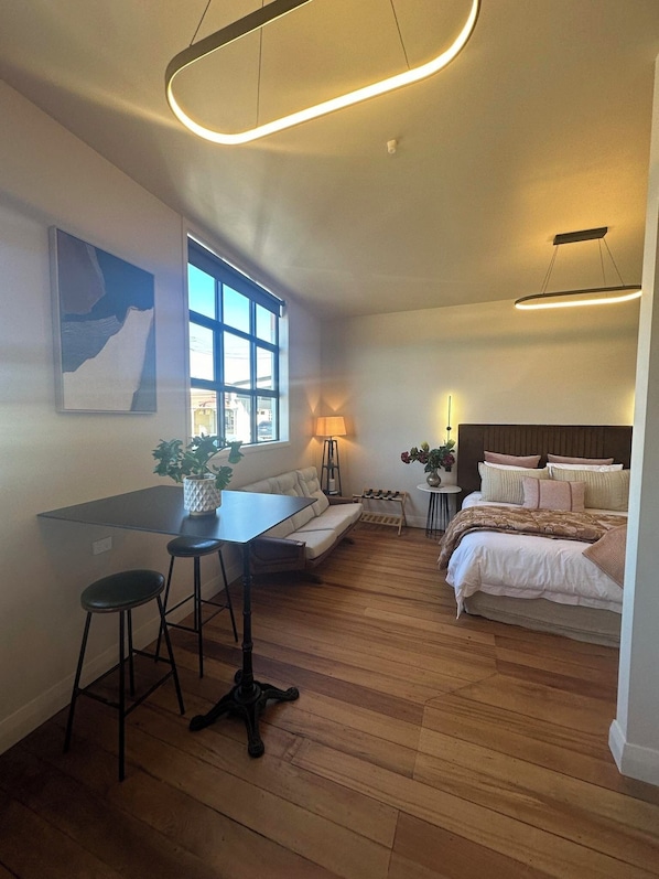 Une chambre moderne avec un grand lit, un bureau avec une chaise, un canapé et une fenêtre.