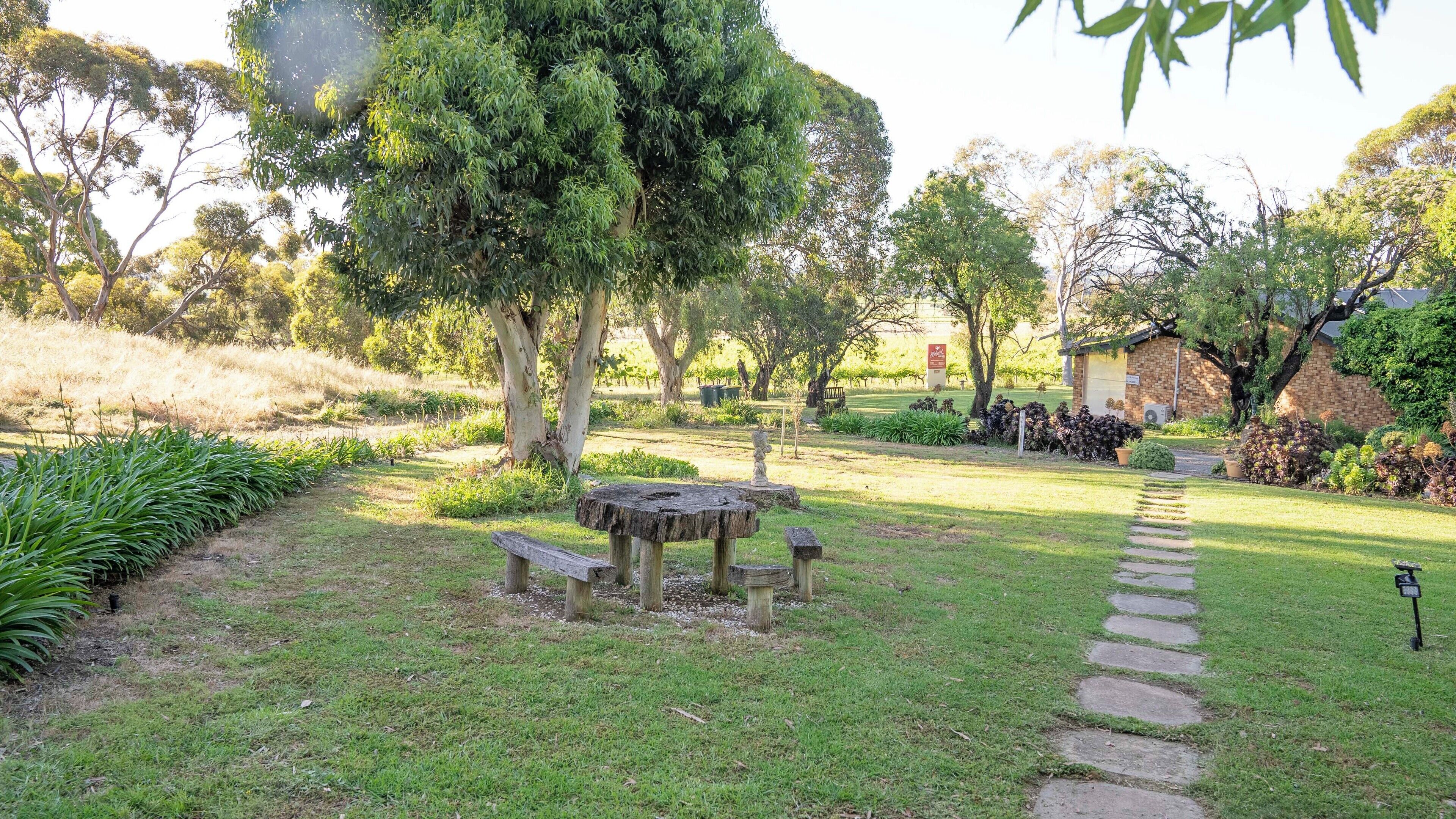 A garden with a stone table, a stone path, and various plants.
