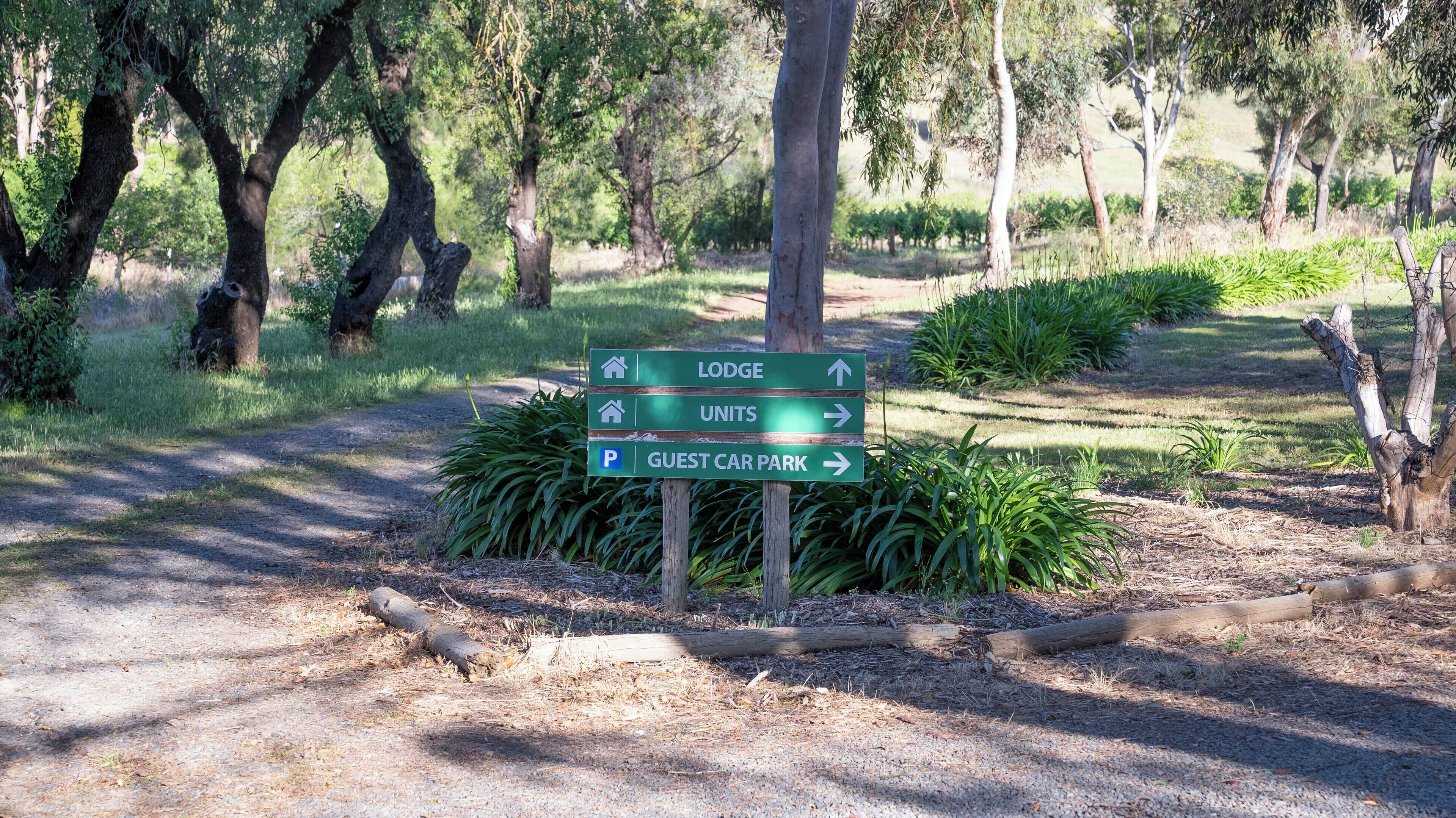 Señal direccional con flechas indicando 'Lodge', 'Unidades' y 'Estacionamiento para Huéspedes'.