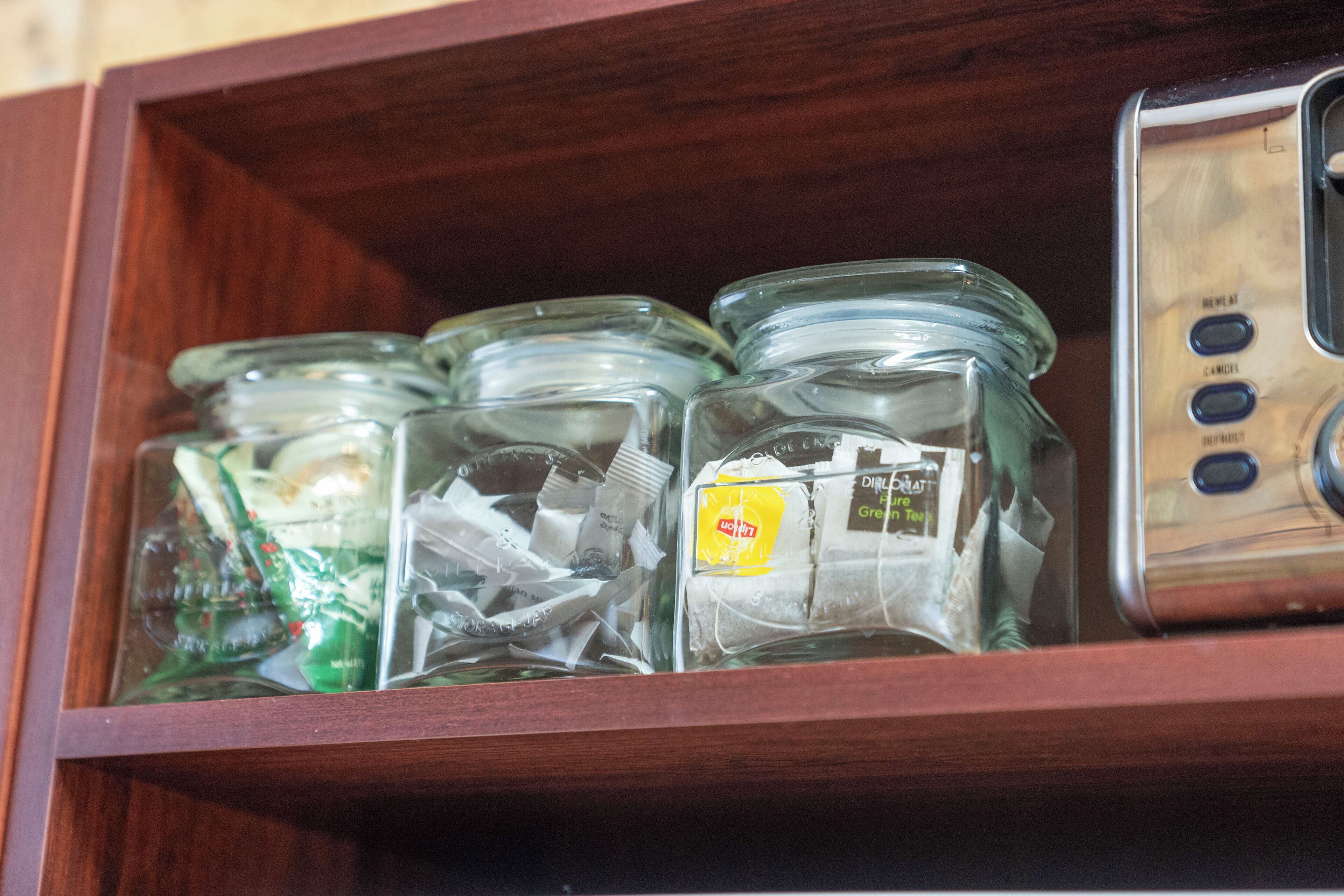 A wooden shelf with glass jars containing various items, including a yellow tag and a green tag.