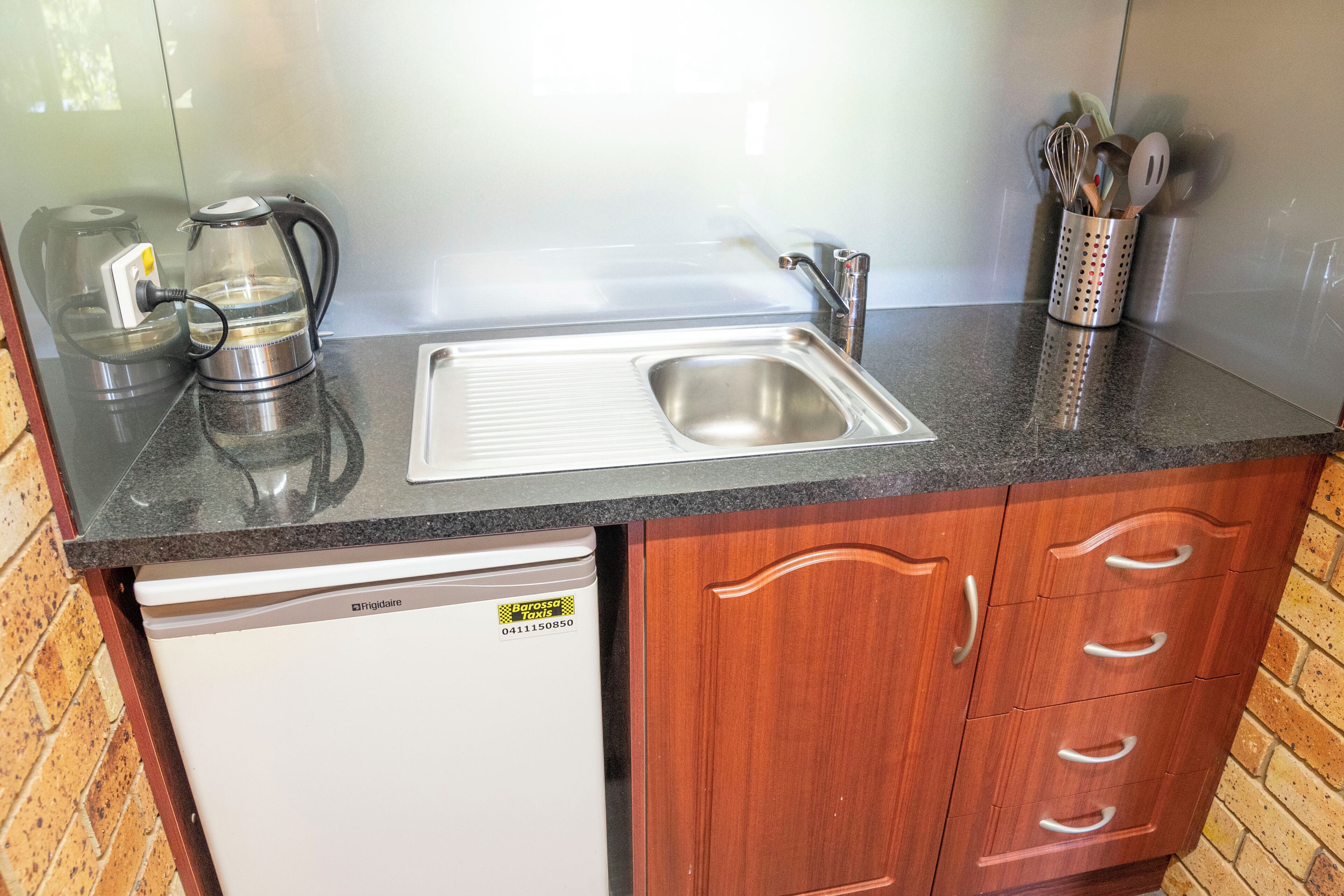 A kitchen with a stainless steel sink, a coffee maker, and a dishwashing machine.
