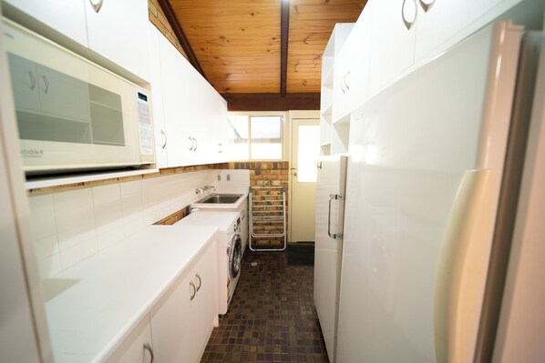 Una cocina compacta con electrodomésticos blancos, un revoque de ladrillo y techo de madera.