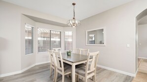 A dining room with a wooden table and chairs, a chandelier, and a large mirror on the wall. - Spacious 6-bedroom 3 Bathroom Entire House in charming Gilbert Sleeps 12 (Gilbert)