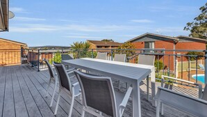 Una terrazza con tavolo e sedie, con vista su una piscina e edifici residenziali.