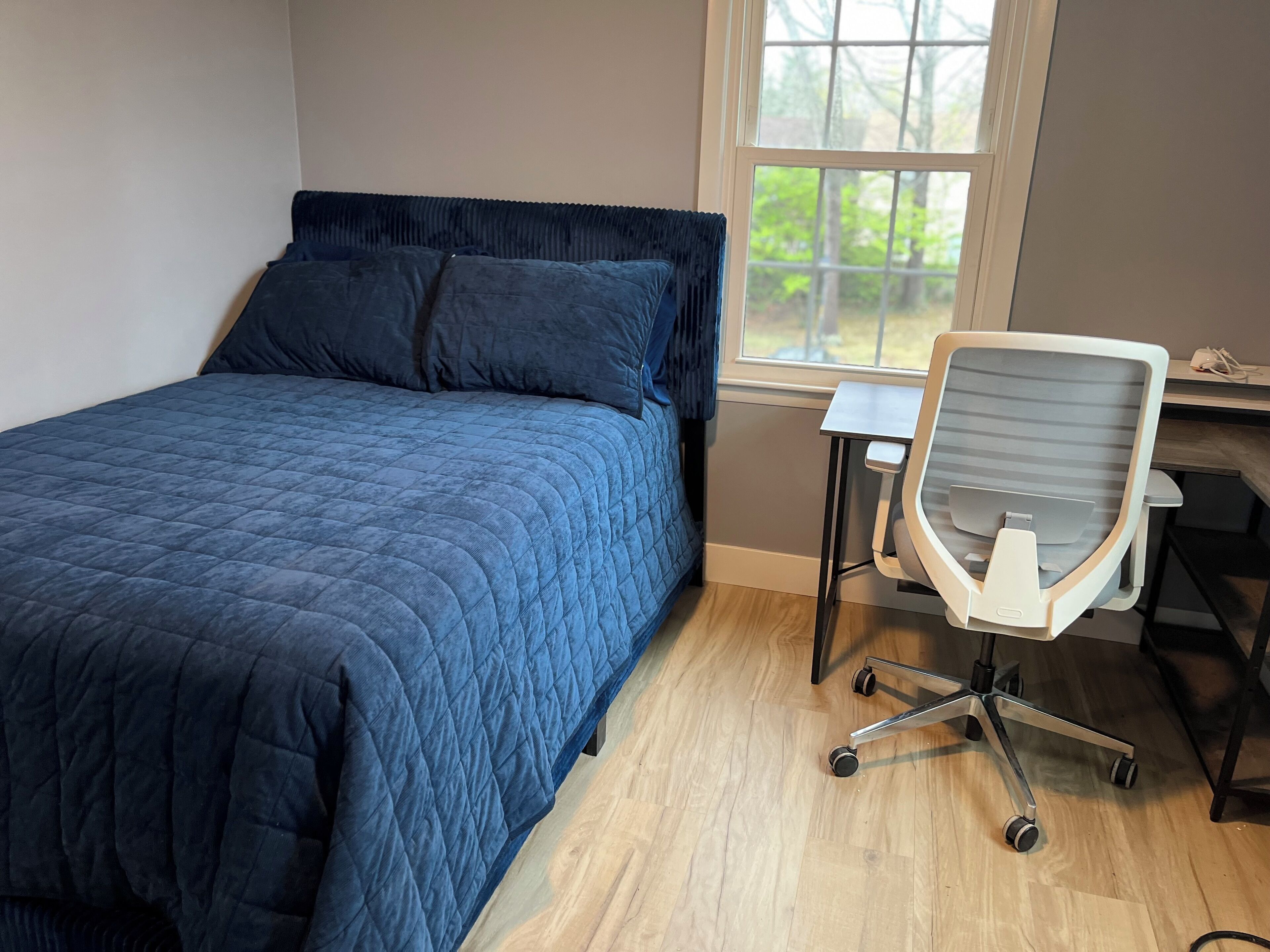A bedroom with a bed, a desk, and a chair.