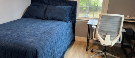 A bedroom with a bed, a desk, and a chair.