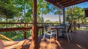 An outdoor patio with a wooden deck, a table with chairs, and a hammock.