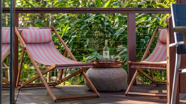 Two striped lounge chairs with a woven stool and a tray with a bottle and glasses on a wooden deck. - Tidewood at Elizabeth beach (Elizabeth Beach)