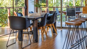 A modern dining area with a wooden table and black chairs, a woven placemat, and a potted plant.