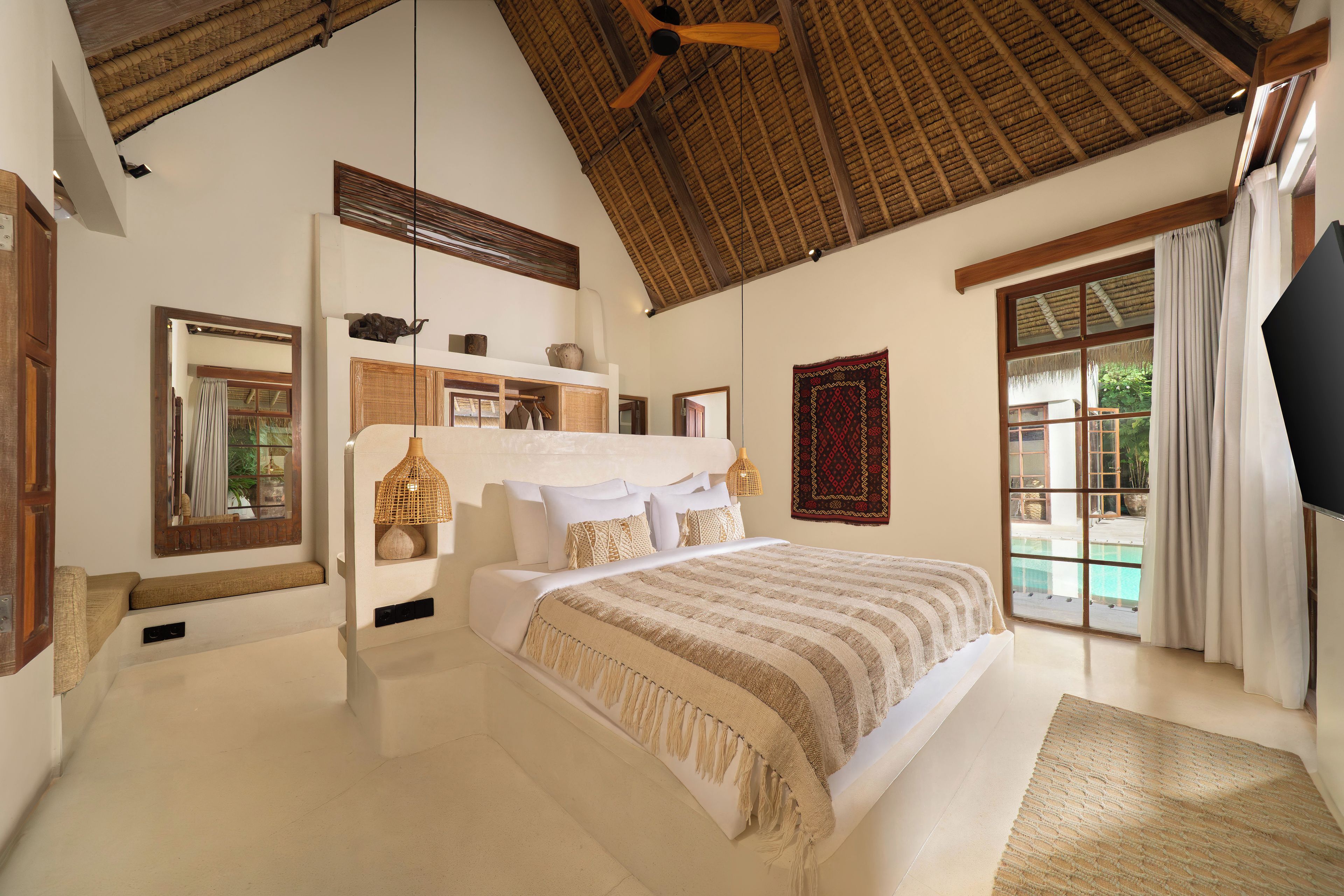 Un dormitorio amplio con una cama grande, ventilador de techo y vistas al exterior.