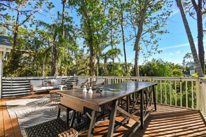 Een terras buiten met een eettafel, stoelen en een bank.