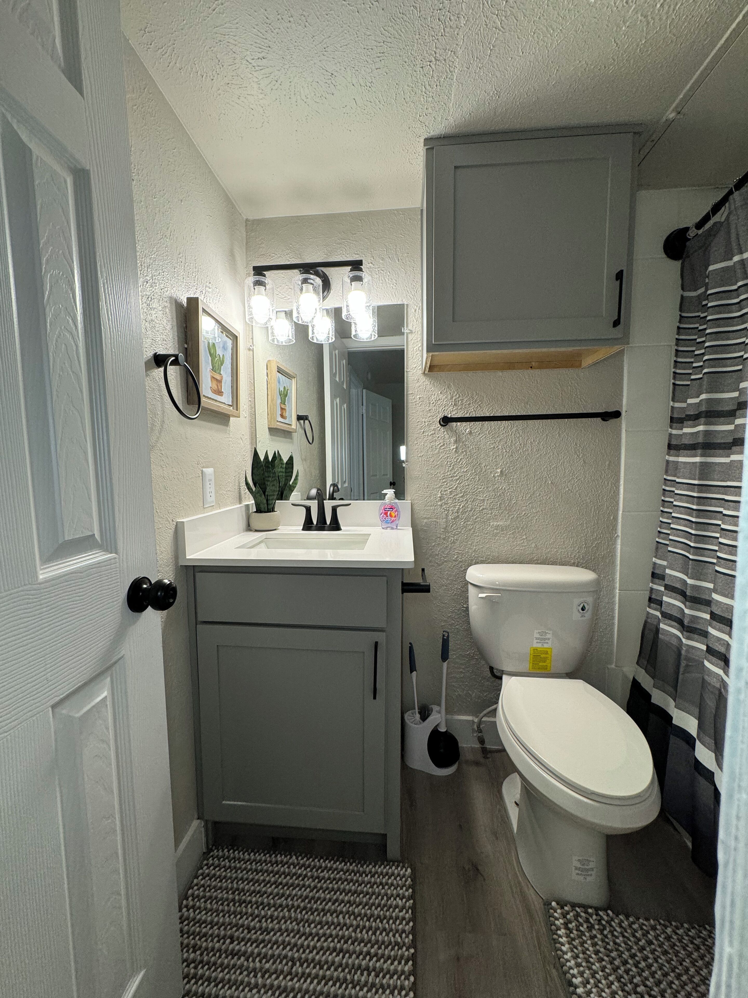 Un bagno compatto con un lavandino bianco, un water e una tenda da doccia.