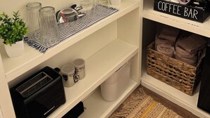 Una cocina con una barra de café, un tostador y una planta en maceta sobre la encimera.