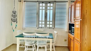 Ein Essbereich mit Tisch und Stühlen, einem Fenster mit Rollläden und einer Holzkabine.