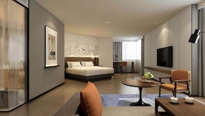 A modern hotel room with a bed, a desk, a TV, and a seating area with a table and chairs. - UrCove by Hyatt Suzhou Shantang Street (Suzhou)
