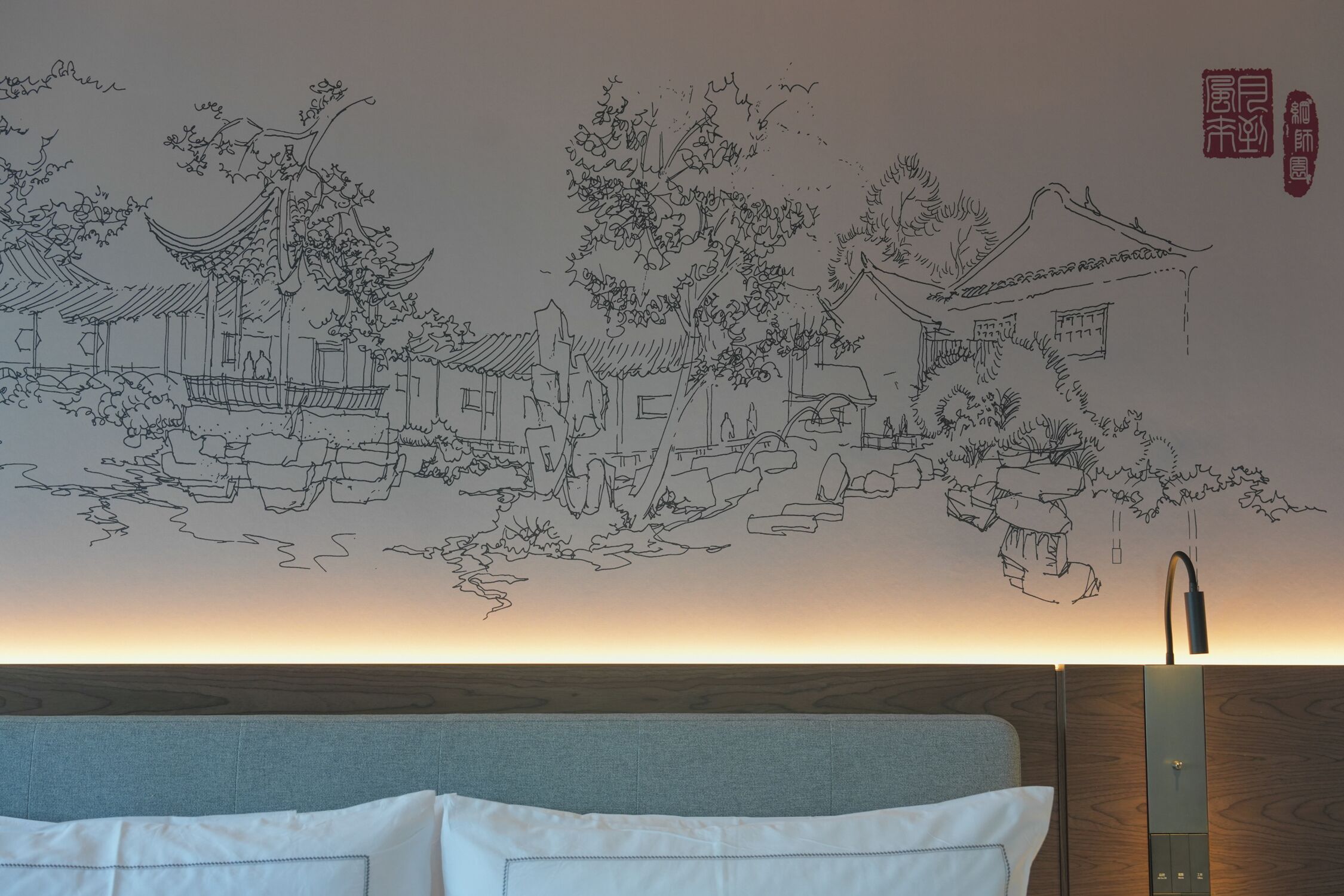 A room with a traditional Chinese mural on the wall, a bed with white bedding, and a wooden headboard.