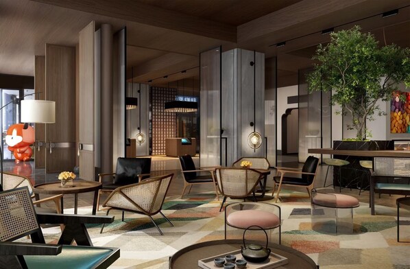 Un moderno vestíbulo de hotel con diversas zonas de estar, una recepción y una pared decorativa con un mural colorido.
