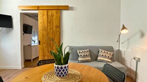 A cozy living area with a wooden table, a potted plant, and a grey sofa with patterned cushions. - MarketHome Ecolodge Plataneras (Lomo Del Balo (Guia I.))