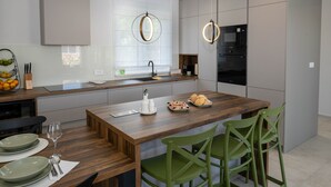 A modern kitchen with a wooden island, green chairs, and a built-in oven. - Holiday House Jewel With Private Pool (Krk)