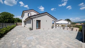 A modern house with a paved driveway, a stone wall, and a clear blue sky. - Holiday House Jewel With Private Pool (Krk)