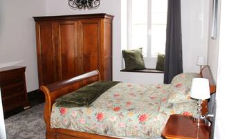 A bedroom with a wooden bed, a dresser, a window with a view, and a chandelier.