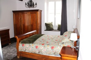 Ein Schlafzimmer mit einem hölzernen Bett, einem Schminktisch, einem Fenster mit Blick und einer Kristallleuchter.