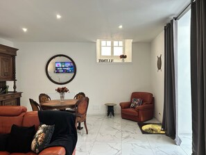 Un saló amb televisió, taula de dinar, sofà, cadira i llar de foc.
