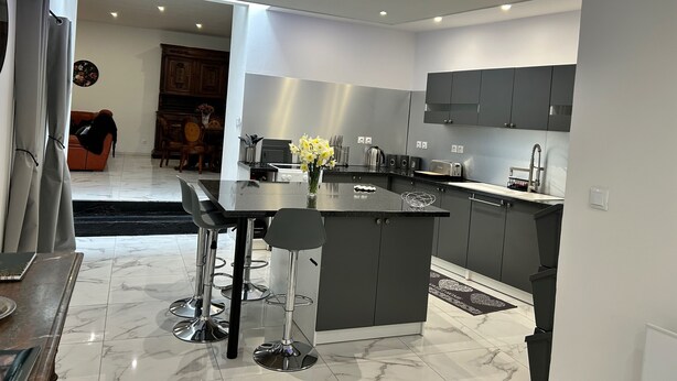 A modern kitchen with a central island, grey cabinets, and a blue accent lighting strip.